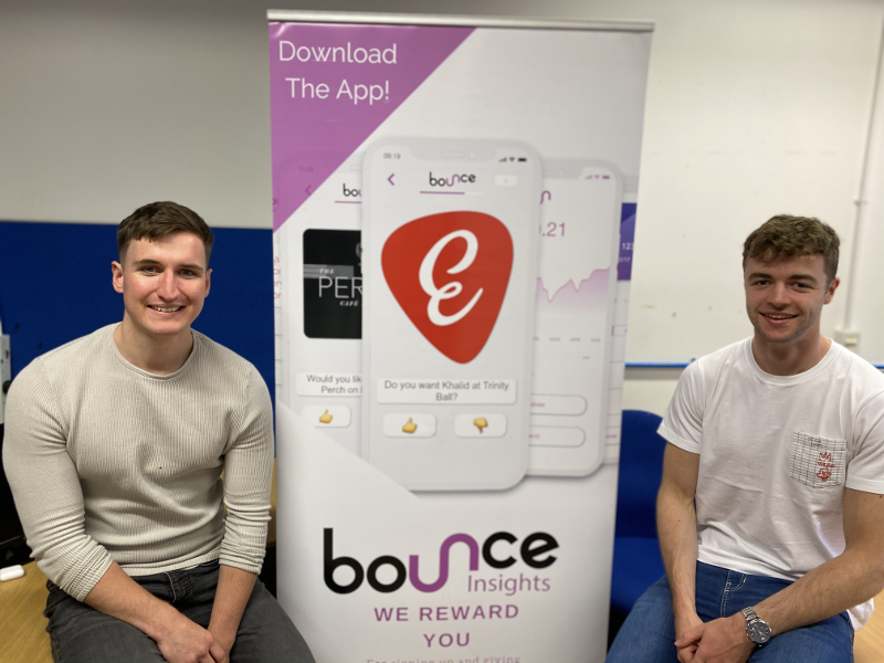 Two young men beside a sign that says Bounce.